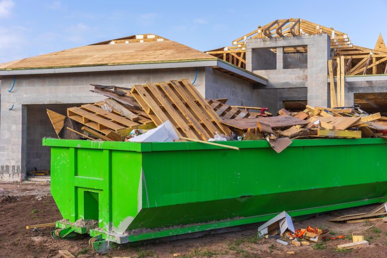 Dumpster full of wooden pallets, boards, and other waste on the site of a single-family house under construction in a suburban residential development